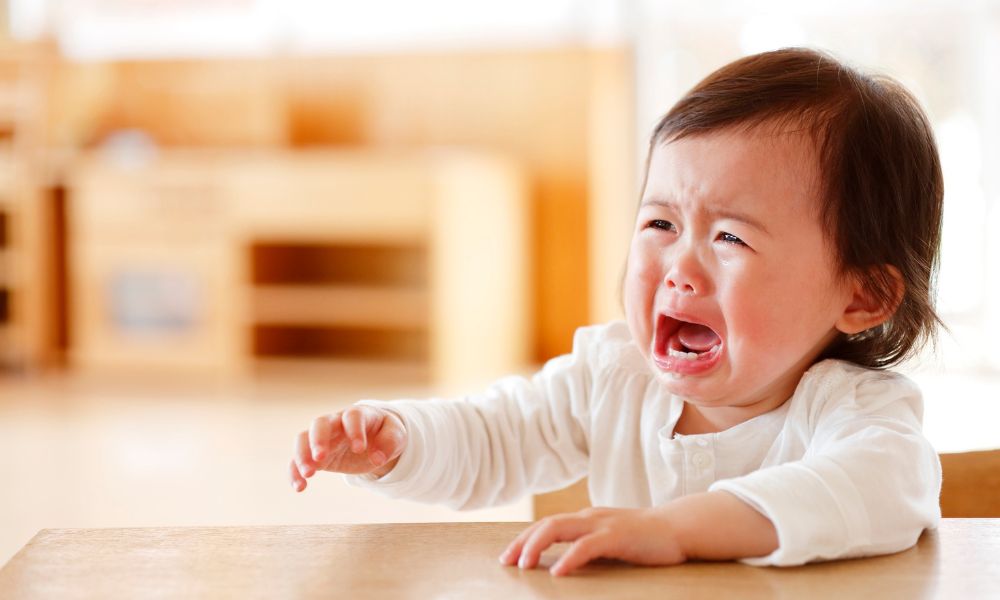テーブルに手を置きながら泣くこども