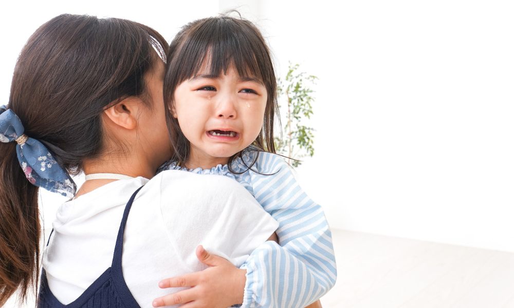 泣いている女の子を抱っこする母親