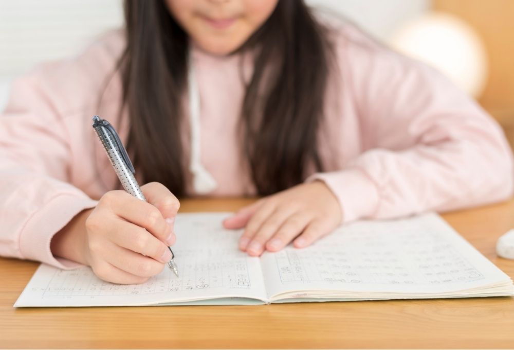 机でノートに書き込む女の子