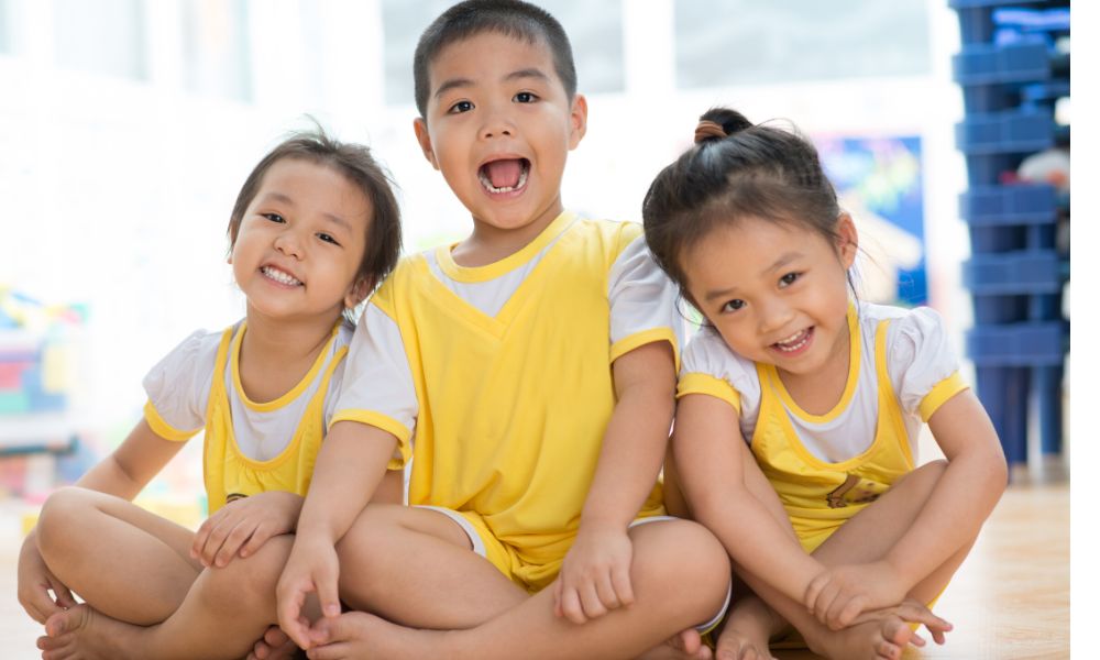 笑顔でこちらを向いて座っている３人のこども