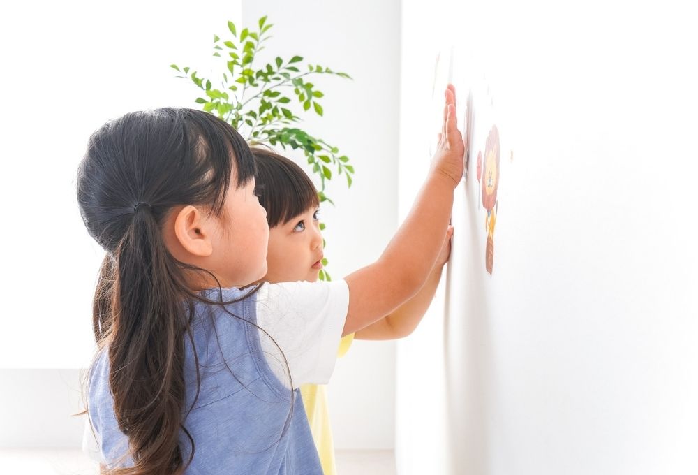 壁にステッカーを貼る女の子ふたり