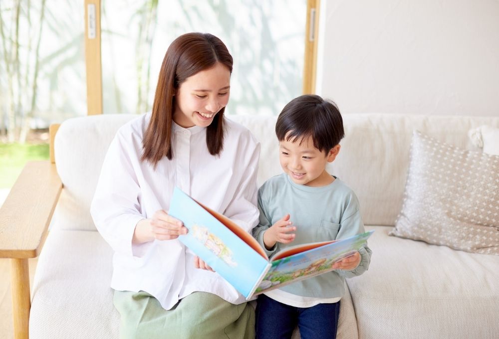 母親と一緒に絵本を読んでいる子ども