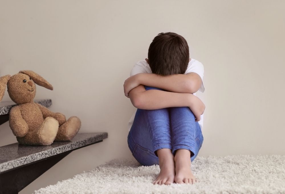床に座り泣いている様子のこども