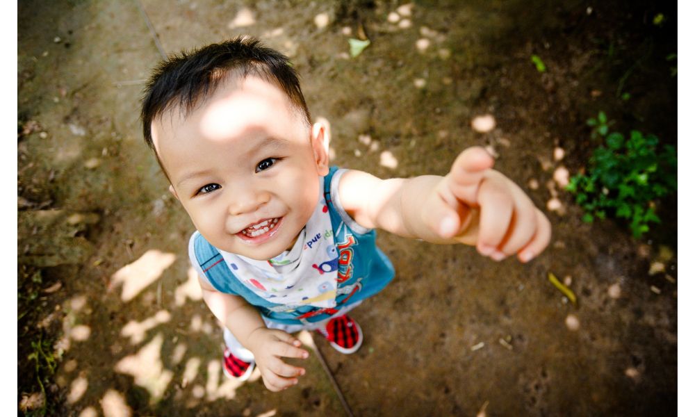 外で空を指さす笑顔のこども