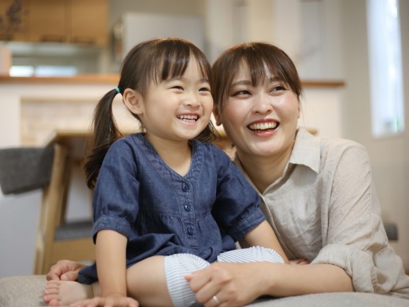 室内で寄り添って笑う母と娘