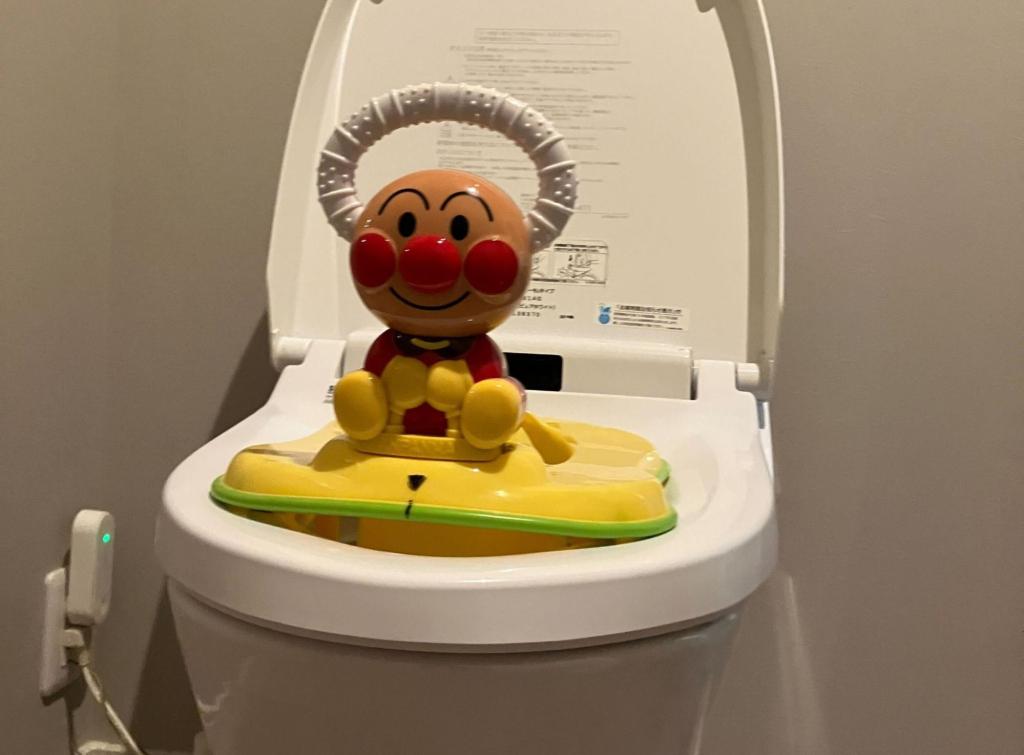 アンパンマンのキャラクターがついた黄色い補助便座が洋式トイレに設置されている。