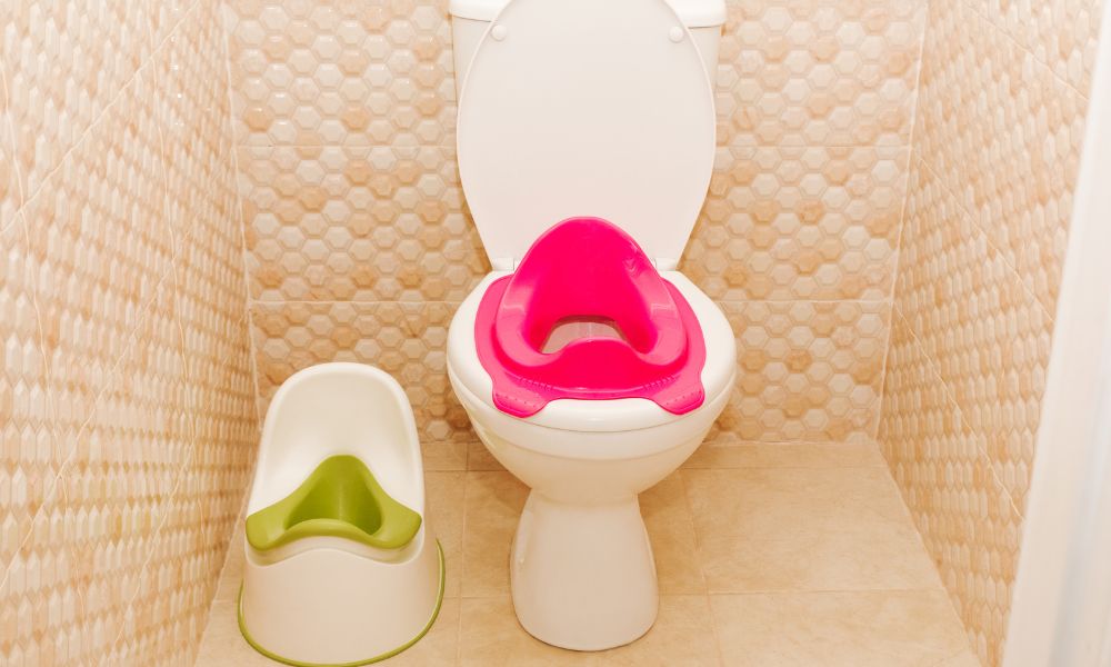 トイレにピンク色の補助便座と、隣に白と緑の子ども用おまるが並んでいる。