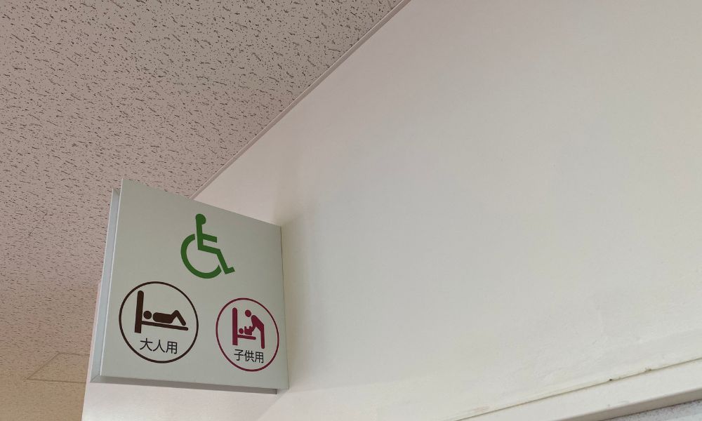 車いすマークと「大人用・子供用」のマークが表示された多機能トイレの案内サイン。
