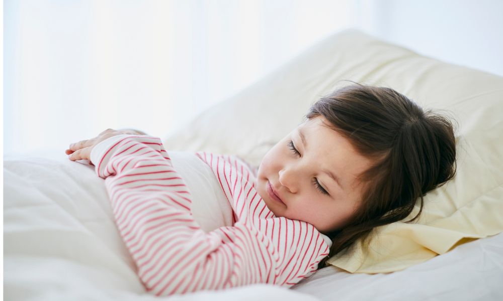 白い布団に入り、ピンクのパジャマを着た女の子が静かに眠っている。