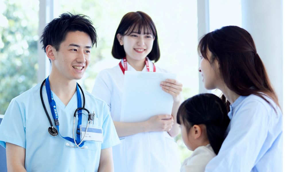 白衣の医師と看護師が、母親と子どもに対して笑顔で話をしている様子。