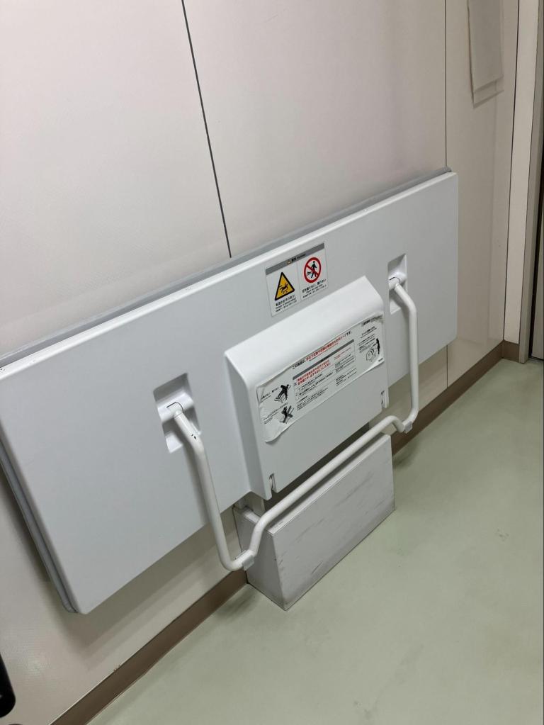 壁面に収納された折りたたみ式の介助ベッド。