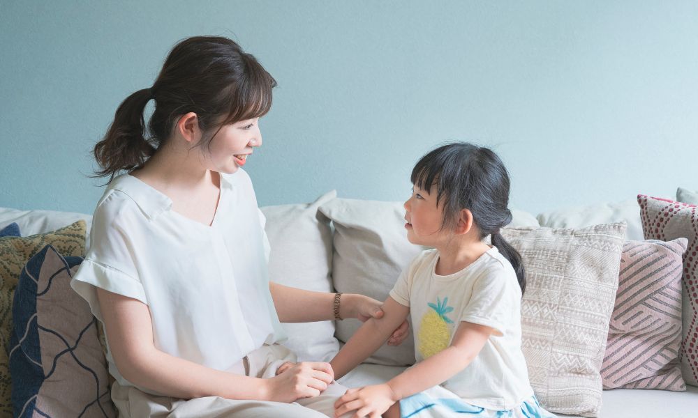 ソファに座った母親と子どもが向き合って会話している場面。