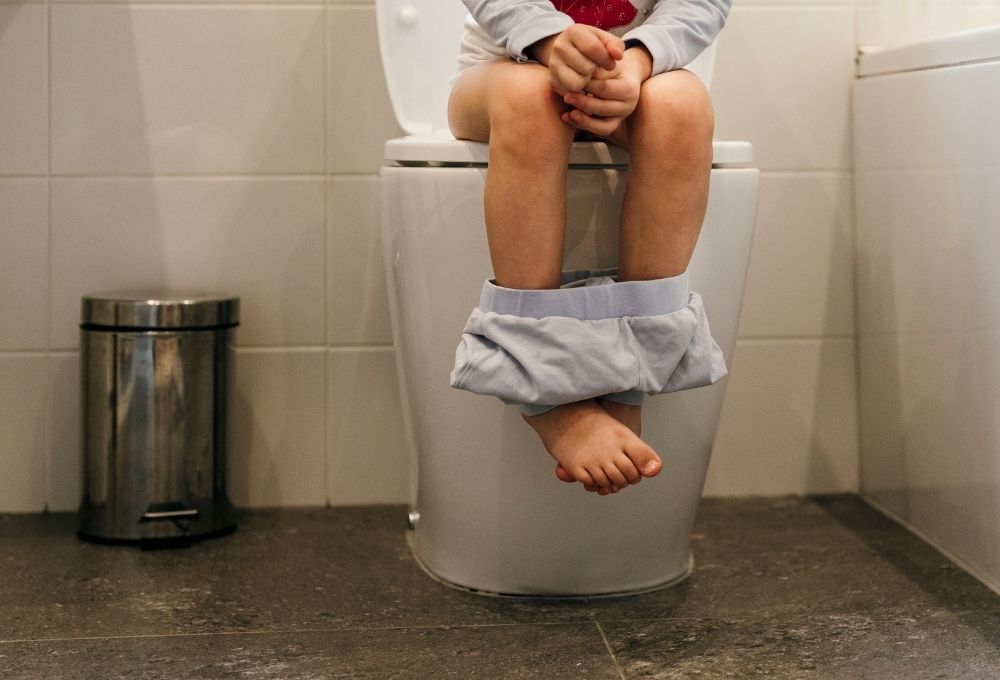 トイレに座っているが排泄できずに脚をぶらつかせている子どもの様子