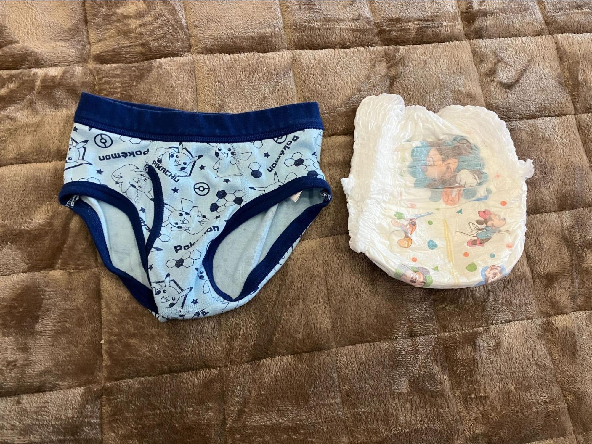 茶色の布の上に子ども用のパンツとオムツが並べて置かれている