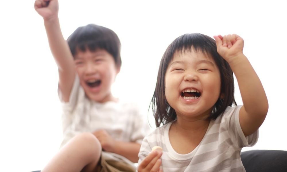 手を上げて笑顔を見せ、嬉しそうに喜んでいる複数の子どもたち