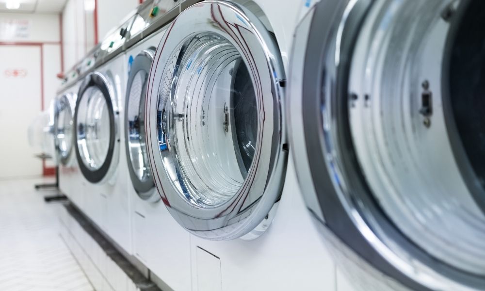 コインランドリーに並ぶドラム式洗濯機を斜めから撮影した写真です。金属とガラスの質感が強調され、清潔で整った空間の印象を与えています。