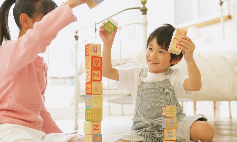 室内で積み木を積み上げて遊ぶ、笑顔の子どもたちの様子