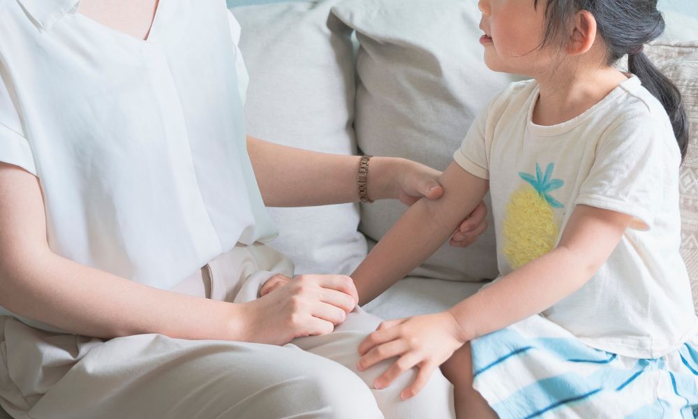 子どもが椅子に座る母親に話しかけている様子