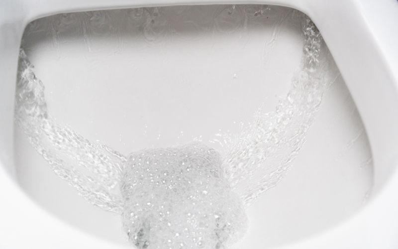 便器の中を水が勢いよく流れているクローズアップ。排泄後に水を流す瞬間を捉えた写真で、すっきりとした感覚や不快の解消を象徴している